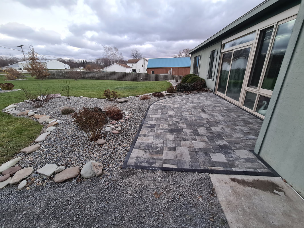 Paver patio with river rock landscape bed in Oswego County